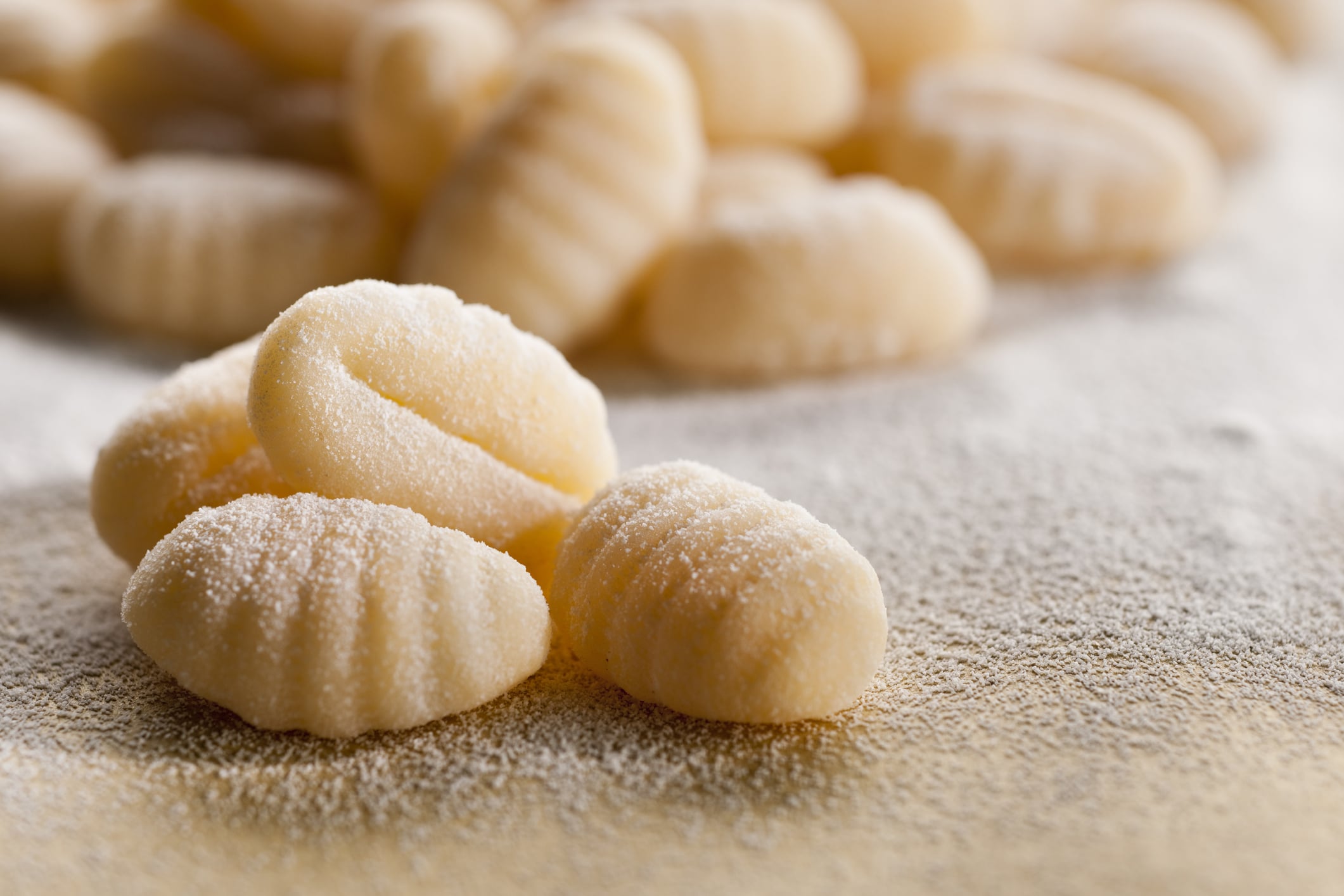 A pile of fresh,homemade potato dumplings on a floured surface.