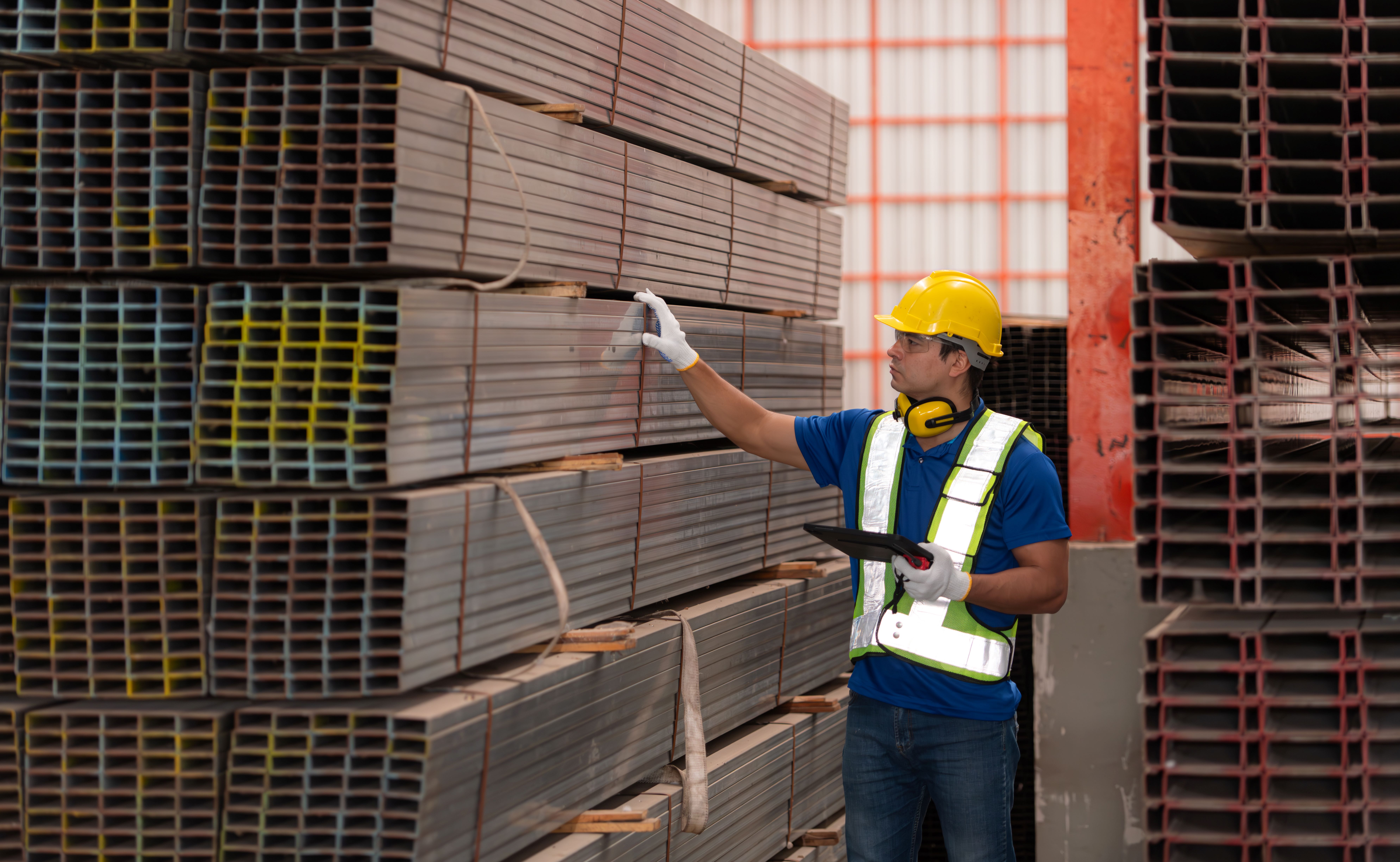 Man in factory, wearing  hard hat inspecting 